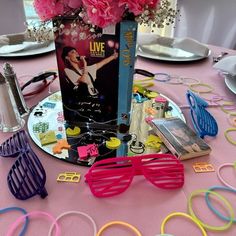 the table is covered with pink flowers and various items like sunglasses, books, and magazines