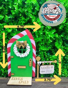 a green door with a christmas wreath on it next to a sign that says north pole