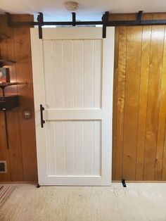 an open white door in a room with wood paneling on the walls and floor