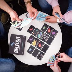 several people sitting around a table holding cards and playing with each other on their hands