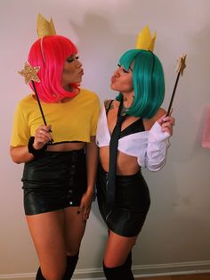 two women dressed in costumes standing next to each other and one is holding a wand