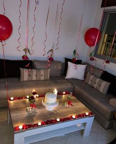 a living room filled with lots of furniture covered in red and white balloons hanging from the ceiling