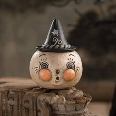 a close up of a small figurine wearing a witches hat on top of a tree stump