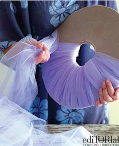 a woman holding a purple fan in her hands and wearing a blue kimono with flowers on it