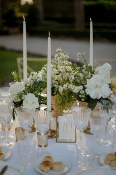 the table is set with white flowers and candles