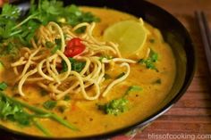 a bowl filled with noodles and vegetables on top of a wooden table