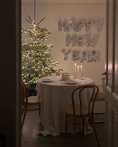 a dining room table with two candles on it and a christmas tree in the background