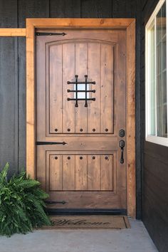 a wooden door sitting next to a green plant