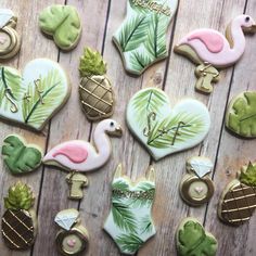 decorated cookies with flamingos, pineapples and palm leaves on a wooden table