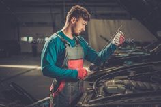 a mechanic working on the hood of his car while looking at something in front of him