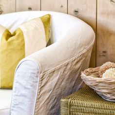 a wicker basket sitting on top of a chair next to a pillow and pillows