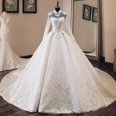 a white wedding dress on display in front of a mirror and mannequins