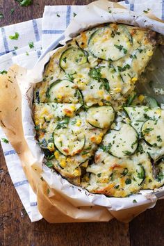 a pizza with zucchini and cheese in a pie pan on a wooden table