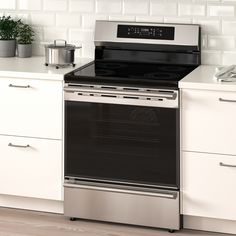 an oven with the door open on a kitchen counter top next to white cabinets and drawers