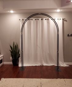 a living room with a white curtain and a black iron arch on the wall next to a potted plant