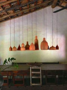 a number of vases hanging from a ceiling in a room with wooden tables and chairs