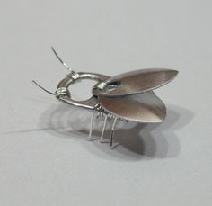 a pair of silver earrings sitting on top of a white table