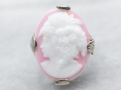 Sweet and full of detail, this Art Deco cameo ring is something special! The filigree is impressive, created using the die-stamping method that produces very fine detail while remaining strong and resilient. The pink glass cameo depicts a woman with 1920s styling, flowers set in curls, and an open neckline. Metal: 14K White Gold Gem: Glass Cameo Gem Measurements: 13.1 x 18.0 mm, Oval Ring Size: 3.25 SKU #: A36203 Each piece has been identified and graded by a Graduate Gemologist who has been cer Styling Flowers, Filigree Ring Gold, Art Deco Pink, Estate Ring, Estate Rings, Cameo Ring, Ring White Gold, Ring Antique, Oval Ring