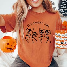 a woman wearing an orange shirt that says it's spooky time