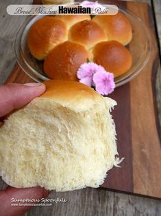 a person holding a piece of bread in front of a plate with rolls on it