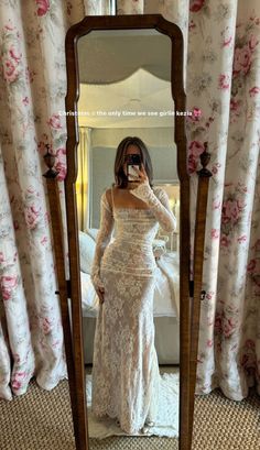 a woman taking a selfie in front of a mirror wearing a wedding dress and holding a camera