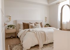 a bedroom with white walls and neutral colored bedding is pictured in the foreground