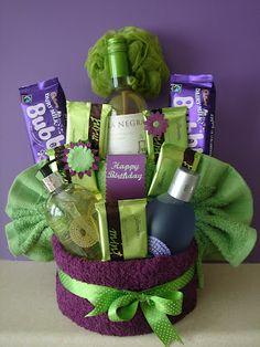 a wine bottle and chocolates in a purple gift basket with green ribbon around it