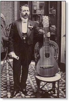 a man in a tuxedo standing next to an acoustic guitar on a chair