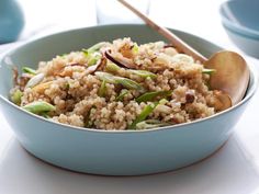 a bowl filled with rice and vegetables on top of a white tablecloth next to blue dishes