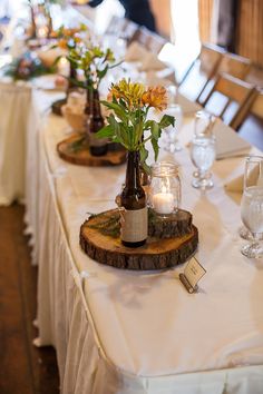 there are many vases with flowers in them on the tables at this wedding reception