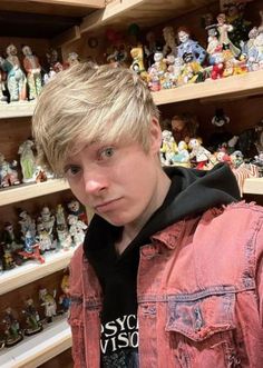 a young man standing in front of shelves filled with figurines