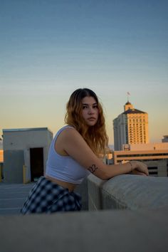 a woman leaning on the edge of a building with her arm resting on a railing