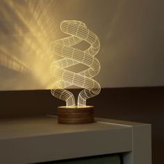 a white lamp sitting on top of a table next to a wooden chair and wall