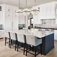 a large kitchen with white cabinets and marble counter tops, along with bar stools