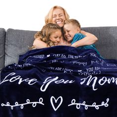 two girls and a boy cuddle under a blanket that says i love you mom