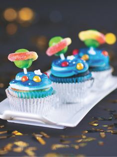 three cupcakes on a plate with candy toppings