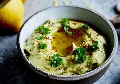 a white bowl filled with hummus and cilantro on top of a table