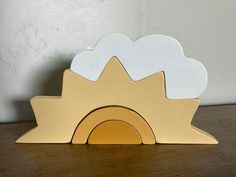 a wooden toy house with clouds on it's roof, sitting on a table