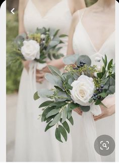 three bridesmaids in white dresses holding bouquets with greenery and flowers on them