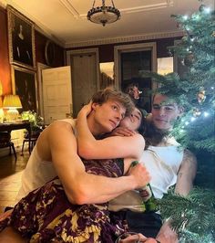 two people hugging each other in front of a christmas tree