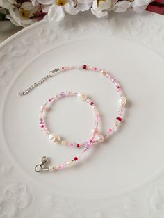 a white plate topped with two bracelets on it's side and flowers in the background