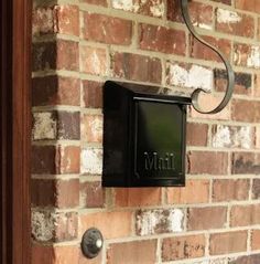 a black mailbox mounted to the side of a brick wall next to a door