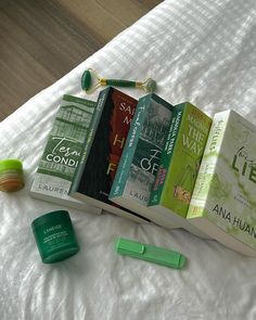 there are many books on the bed next to some lip balm and an earbud