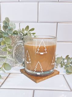 a glass mug filled with coffee sitting on top of a counter next to a potted plant