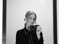 a woman taking a selfie in front of a mirror with her camera up to her ear