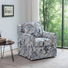 a blue and white chair sitting in front of a window next to a coffee table