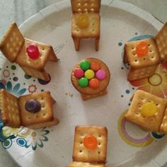 small crackers are arranged on a plate with candies in the shape of chairs