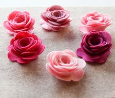 several pink and red felt flowers sitting on top of a piece of paper