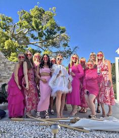 a group of women standing next to each other wearing pink dresses and holding skis