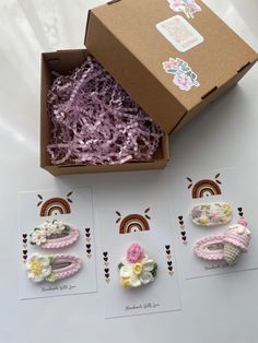 an open box with three pairs of crochet shoes in it next to some cards